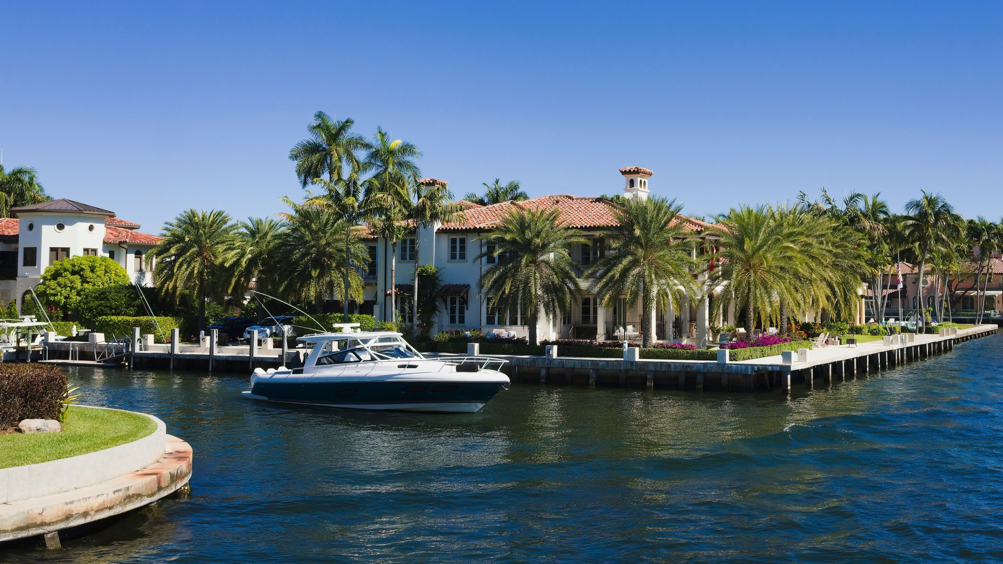 Waterfront estate with palms and a motor yacht across a South Florida canal